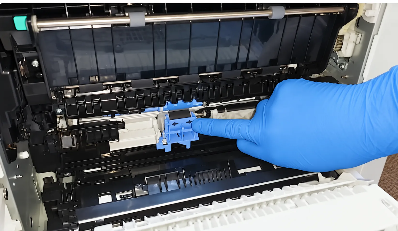 Technician inspecting the Tray 2 feed roller area of an HP LaserJet Managed E60155dn during an onsite service visit