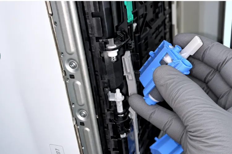 Technician inspecting a paper feed roller on an HP LaserJet Enterprise MFP M527